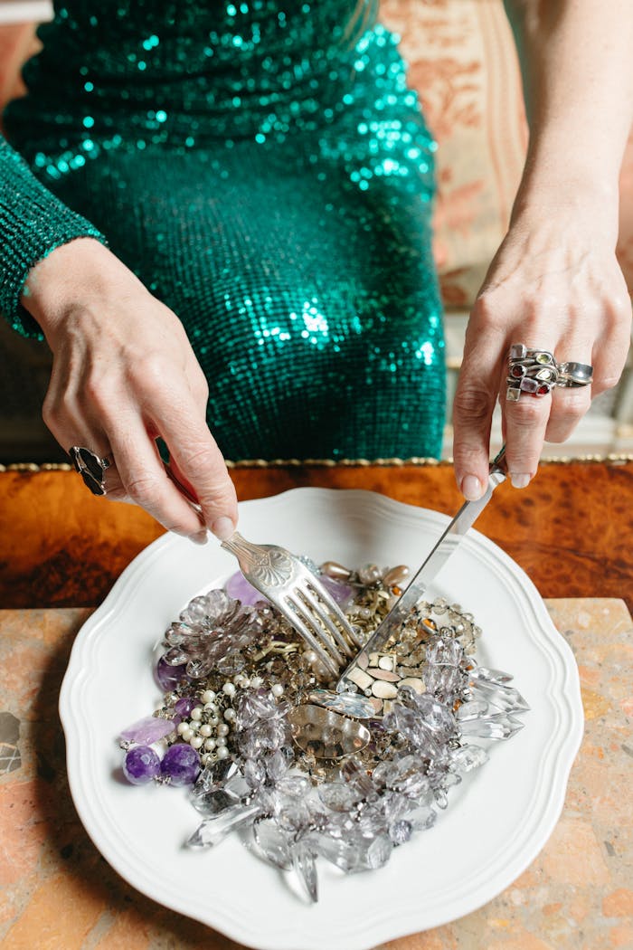 An elegant woman in a sparkling dress dining on jewelry, symbolizing luxury and wealth.