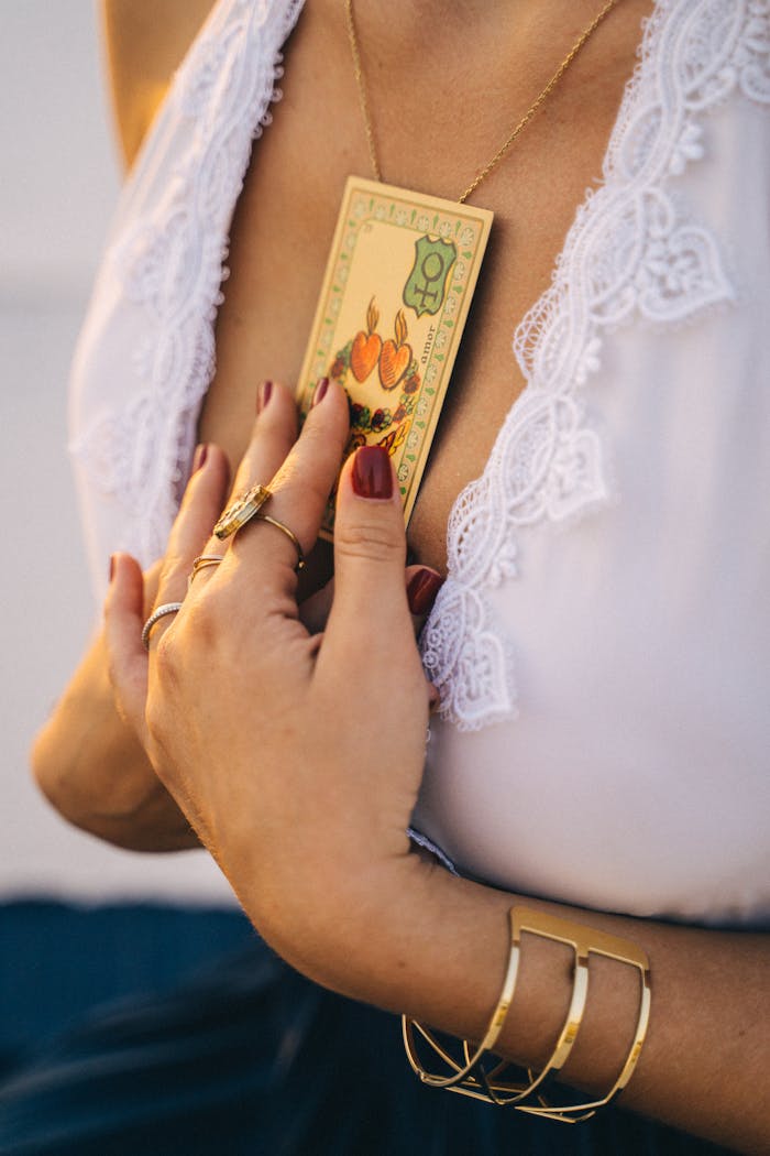 Close-up of a woman's hands holding a tarot card near her heart, showcasing elegance and spirituality.